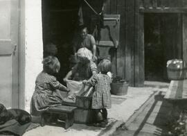 Kinder beim Wäschewaschen, im Hintergrund Schupfe