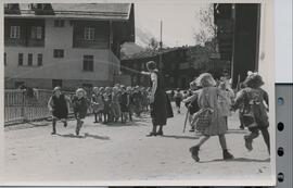 Tante Hermine mit ihren Kindergartlern beim Spielen vor dem alten Schulhaus
